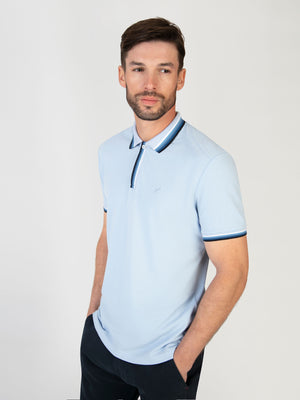 A man wearing a sky blue polo with contrast detail, for the summer season. Menswear UK.