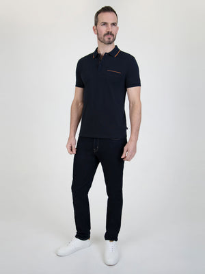 Man wearing a Tonto Navy short-sleeve polo shirt with stylish details, paired with dark jeans and white sneakers.