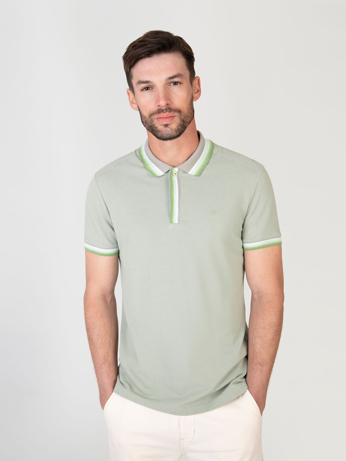 A man wearing a sage green polo with white shorts for the summer time. 