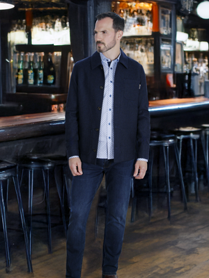 A man wearing the wool blend navy jacket and mishmash denim jeans.